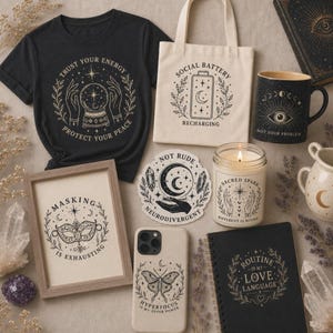 A flat lay of various witchy-themed products on a dark background, including a black t-shirt, a tote bag, a mug, a framed print, a phone case, a candle, and a notebook.