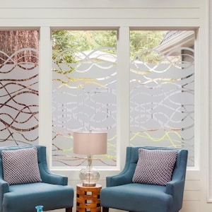 May include: Three-panel window with frosted glass film featuring a flowing, abstract design in white. The windows are framed in white and set in a bright room with blue armchairs and a lamp. The design adds privacy and a decorative element.