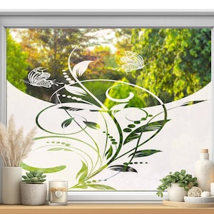 Peut inclure: Un film pour fenêtre blanc présentant un motif botanique translucide avec des vignes entrelacées, des feuilles et deux papillons. Le motif est semi-transparent, laissant passer la lumière tout en masquant la vue sur les arbres extérieurs.