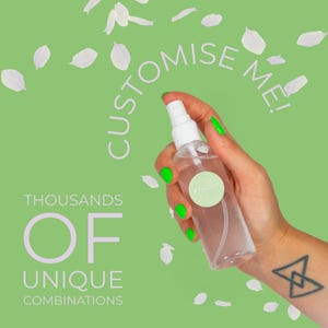 Könnte beinhalten: Eine transparente Sprühflasche mit weißem Deckel wird vor einem grünen Hintergrund mit weißen Blütenblattformen gehalten. Die Flasche hat ein grünes Etikett. Der Text "CUSTOMISE ME!" und "THOUSANDS OF UNIQUE COMBINATIONS" sind ebenfalls sichtbar.