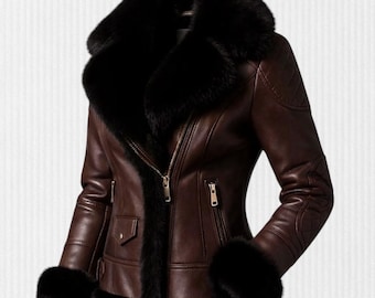 Könnte beinhalten: Braune Lederjacke mit schwarzem Pelzkragen, Manschetten und Besatz. Die Jacke hat einen Reißverschluss, eine kleine Tasche und Steppdetails an den Schultern. Die Jacke ist auf Wärme und Stil ausgelegt.