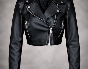 May include: A black leather jacket with a classic biker style. The jacket features a notched collar, silver zippers, and snap details on the shoulders. The cropped design and fitted silhouette create a sleek, edgy look.