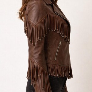 K&ouml;nnte beinhalten: Braune Lederjacke mit Fransen an Schultern und &Auml;rmeln. Die Jacke hat einen Rei&szlig;verschluss und ein klassisches Bikerjacken-Design. Ein stilvolles Oberbekleidungsst&uuml;ck.