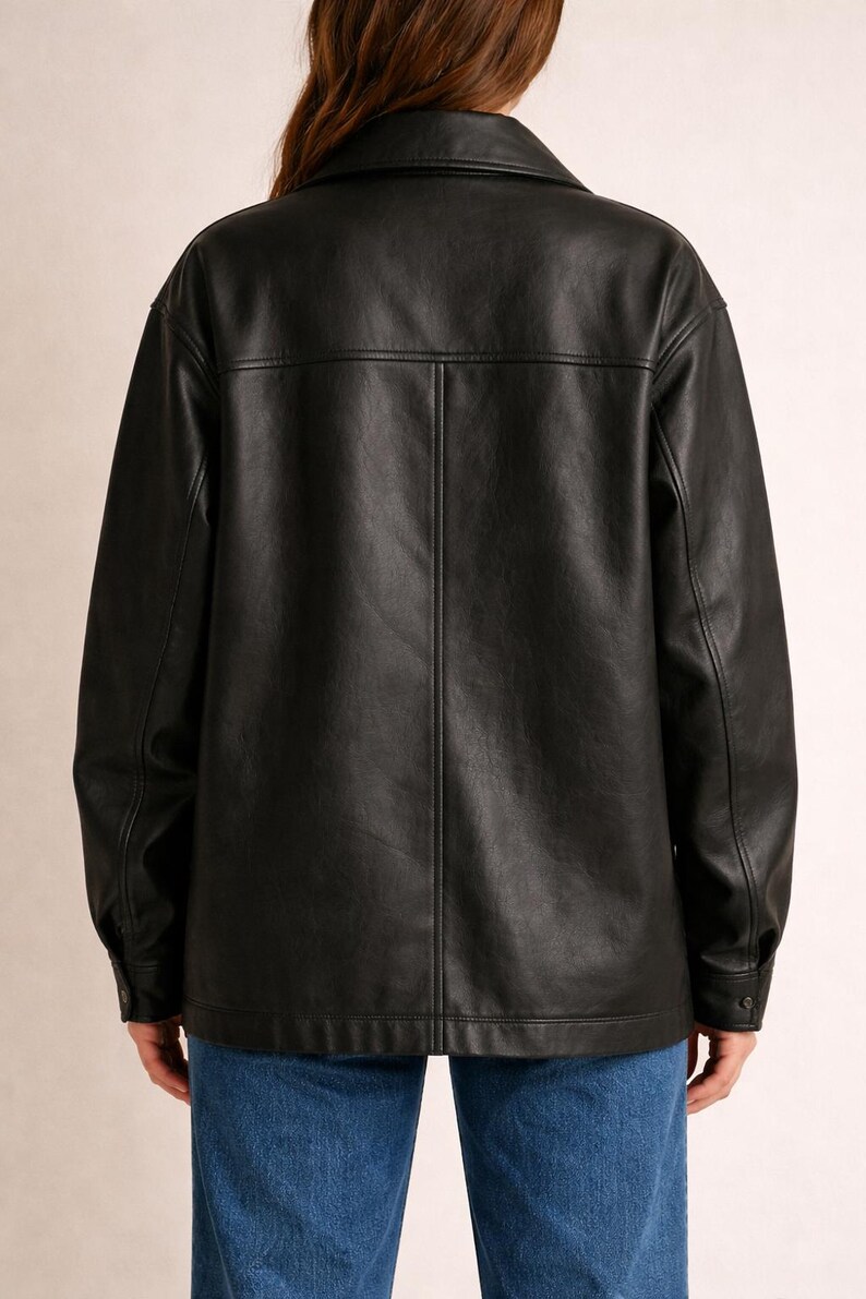 May include: A black leather jacket with a collared neckline and buttoned cuffs. The jacket has a classic design with a button-down front and a tailored fit. The model is wearing blue jeans.