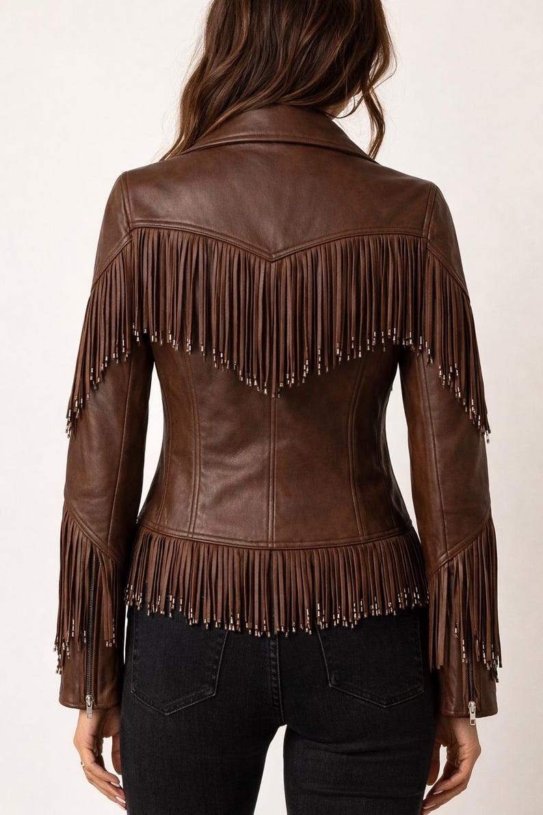 K&ouml;nnte beinhalten: Braune Lederjacke mit Fransen an R&uuml;cken, &Auml;rmeln und Saum. Die Jacke hat einen klassischen Kragen und eine taillierte Silhouette. Die Fransen sind mit kleinen silberfarbenen Nieten verziert. Ein stilvolles Oberbekleidungsst&uuml;ck.