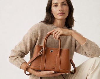 Piccola borsa a mano in pelle martellata, con manico superiore e tracolla removibile.