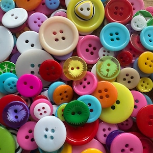 May include: A vibrant assortment of buttons in a range of colours, including red, pink, yellow, blue, and white. The buttons vary in size and have two or four holes. Perfect for sewing and craft activities.