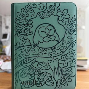 May include: A sage green zipped binder featuring a black line art illustration of a round owl perched on a tree branch surrounded by stylised leaves and flowers. The word vaultx is printed in black at the bottom left corner of the cover.