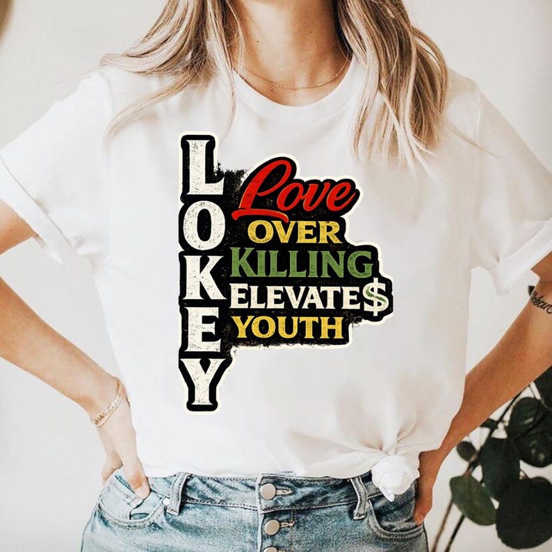 Może przedstawiać: Biała koszulka z kolorowym wzorem graficznym. Projekt przedstawia słowa "LOKEY" ułożone pionowo po lewej stronie, z napisem "Love Over Killing Elevates Youth" w mieszance czcionek i kolor&oacute;w. Koszulka ma kr&oacute;tkie rękawy.