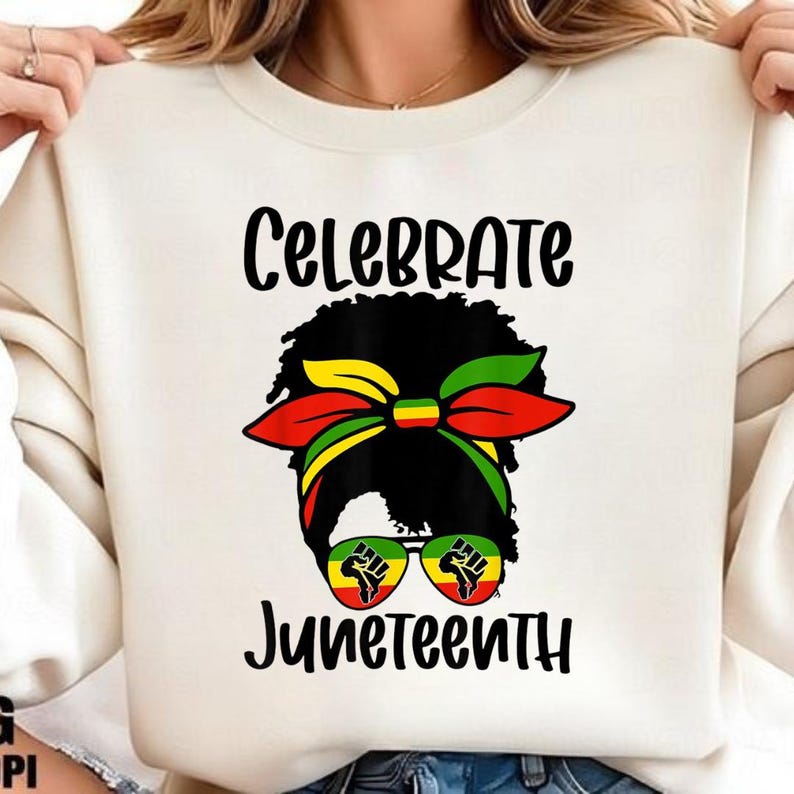 Może przedstawiać: Kremowa bluza z napisem "Celebrate Juneteenth" czarnym pismem. Grafika przedstawia sylwetkę kobiety z kolorową opaską na głowę i okularami przeciwsłonecznymi. Okulary przeciwsłoneczne mają grafikę pięści.