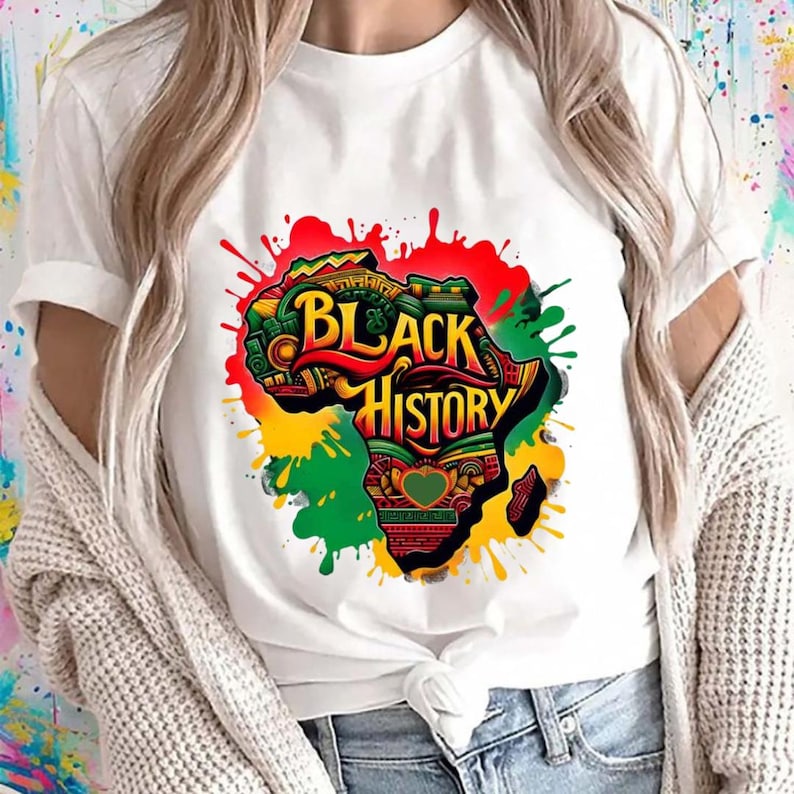Może przedstawiać: Biała koszulka z kolorową grafiką kontynentu afrykańskiego i napisem "Black History". Projekt wykorzystuje kolory czerwony, zielony, ż&oacute;łty i czarny, z efektami rozprysk&oacute;w farby. Odważna koszulka.