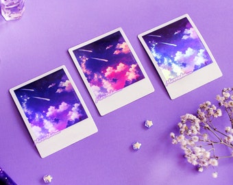 May include: Three white framed prints with a purple, pink, and blue sky with clouds and shooting stars. The prints have the word "moonchild" written on them.