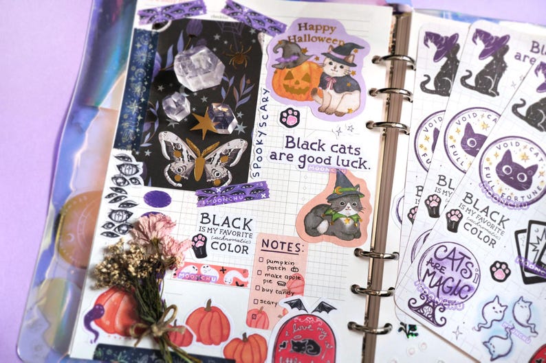 a beautiful halloween scrapbook journal spread of spooky halloween stickers, featuring moonchu's original art sticker sheet about black cats. features several black cat text, including black cats are good luck and i love black cats forever, as well as black cats with witch hats, paw prints, crystal ball, cat ghosts etc.