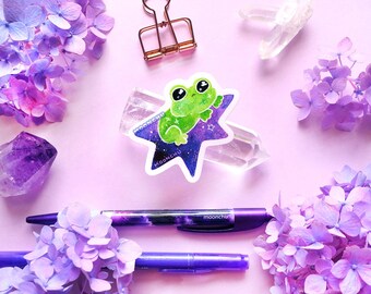 little green frog blasting off to space on a star die cut vinyl sticker | STICKER | original froggy art, frog sticker, space frog
