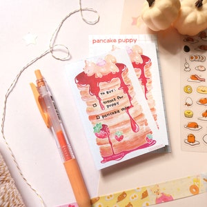 以下が含まれることがあります： 「To Buy!」と書かれたリストと、チェックボックスに「treats for puppy」と「pancake mix」と書かれた、漫画のパンケーキパピーが描かれたステッカーシートです。