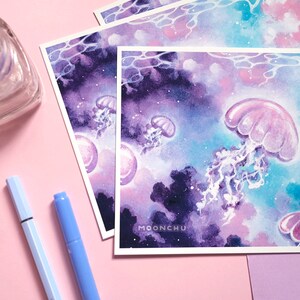Puede incluir: Una pintura de acuarela de medusas nadando en un oc&eacute;ano parecido a una galaxia. Las medusas son rosas y moradas, y el oc&eacute;ano es una mezcla de azul, morado y rosa. La pintura tiene un ambiente de ensue&ntilde;o y et&eacute;reo.