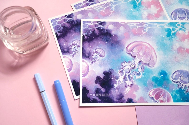 Puede incluir: Una pintura de acuarela de medusas nadando en un oc&eacute;ano parecido a una galaxia. Las medusas son rosas y moradas, y el oc&eacute;ano es una mezcla de azul, morado y rosa. La pintura tiene un ambiente de ensue&ntilde;o y et&eacute;reo.