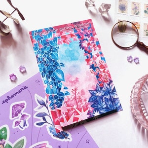May include: A set of two watercolor greeting cards featuring a garden scene with blue and pink flowers and leaves. The cards are titled "through the garden window" and are designed by moonchu.