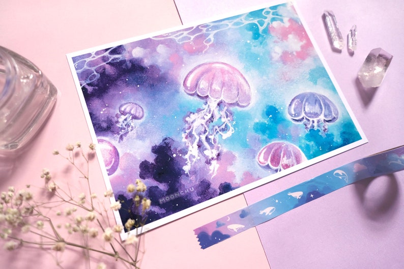 Puede incluir: Pintura acuarela de medusas nadando en un oc&eacute;ano parecido a una galaxia. Las medusas son rosas, moradas y azules, y el fondo es una mezcla de azul oscuro, morado y rosa.