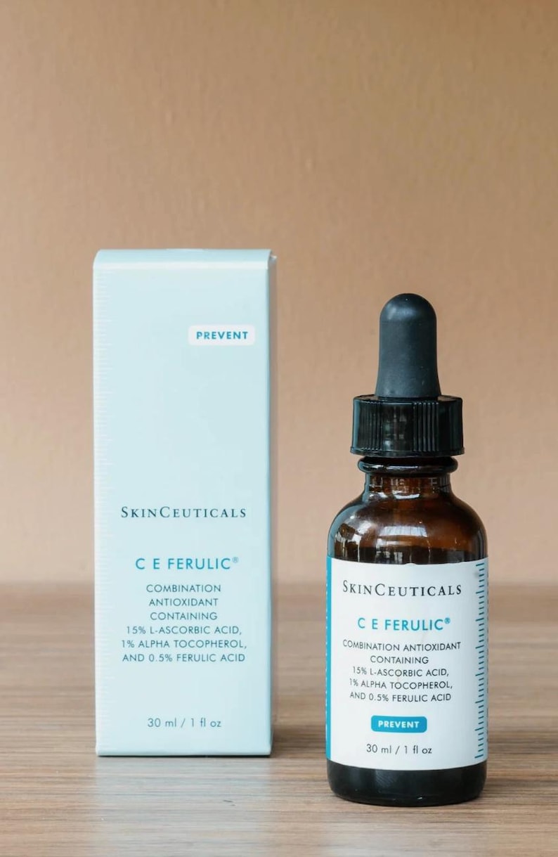 May include: A skincare product set featuring a brown glass bottle with a black dropper and a light blue box. Both items display the "SkinCeuticals C E Ferulic" label, with text detailing ingredients and the word "PREVENT". The bottle and box each contain 30 ml / 1 fl oz.