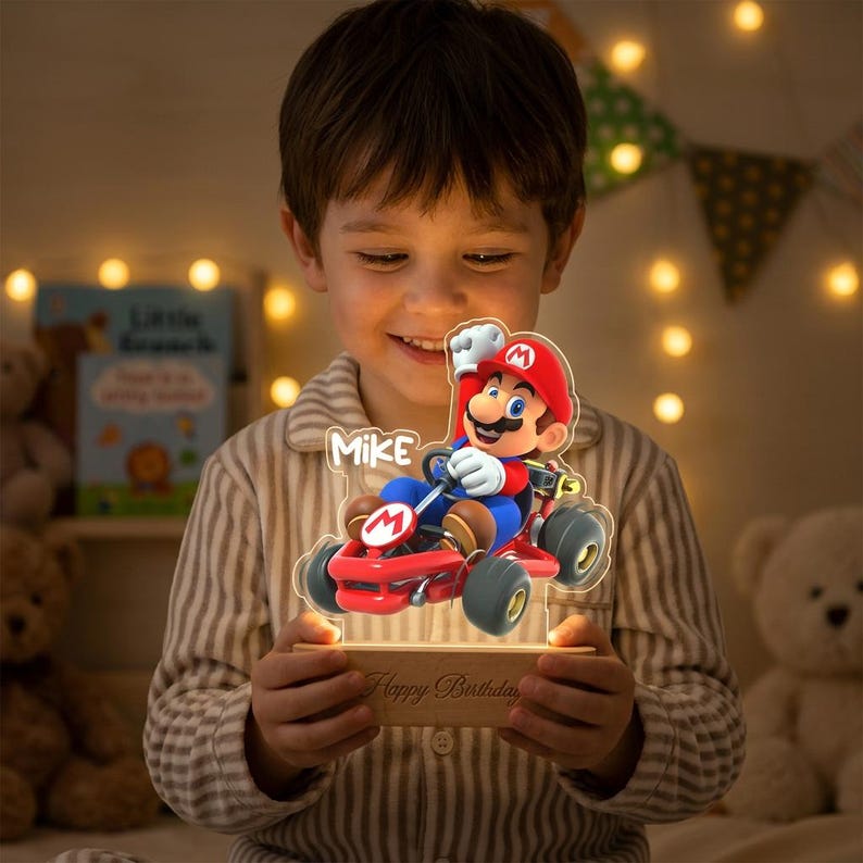 May include: A custom acrylic night light featuring a colourful graphic of Mario driving a red go-kart. The design includes the name Mike and is mounted on a rectangular wooden base with the engraved text Happy Birthday on the front surface.