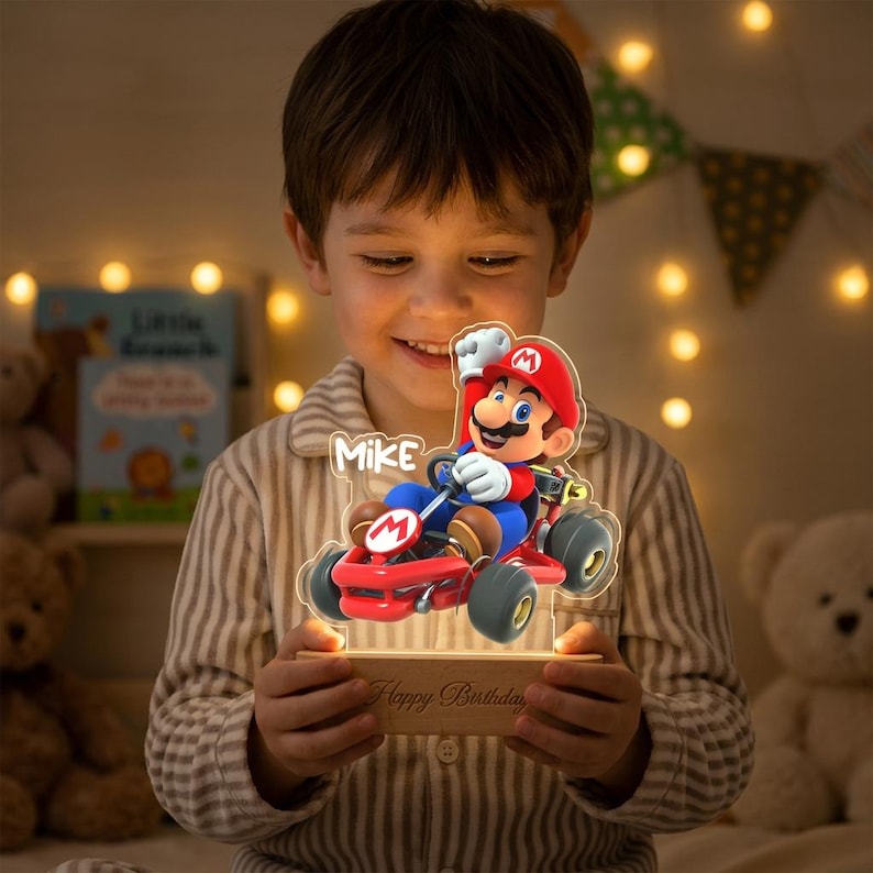 May include: A custom acrylic night light featuring a colorful graphic of Mario driving a red go-kart. The design includes the name Mike and is mounted on a rectangular wooden base with the engraved text Happy Birthday on the front surface.