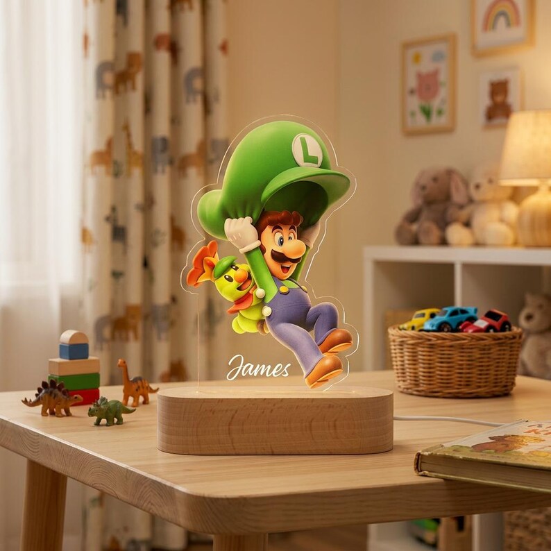 May include: A custom acrylic night light featuring a colorful illustration of Luigi from Super Mario holding a green leaf, with the name James written in white script below. The acrylic cutout is mounted on a smooth, oval-shaped wooden base.