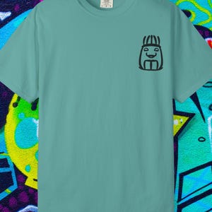 Op de afbeelding: Een zeegroen t-shirt met een kleine zwarte afbeelding op de linkerbovenborst. De afbeelding is een gestileerd gezicht met een lachende uitdrukking. Het t-shirt is gemaakt van een zacht, comfortabel materiaal.