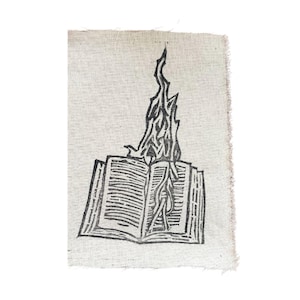 Puede incluir: Una ilustración en blanco y negro de un libro en llamas. El libro está abierto y las llamas se elevan desde el centro de las páginas.