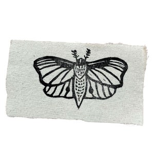 Könnte beinhalten: Schwarz-weiß-Illustration eines Nachtfalters, gedruckt auf einem hellgrauen Stoff.