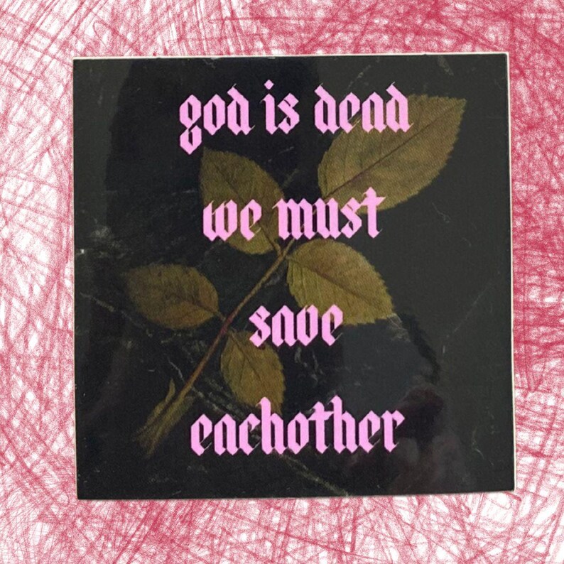 May include: Square sticker with the text "god is dead we must save each other" in pink gothic font. The sticker has a black background with a leaf and stem design in the center. The sticker is on a pink and white background.