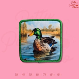 May include: Square patch featuring a detailed image of a mallard duck swimming in water. The duck has a green head, yellow beak, and brown and white body. The patch has a green border and the text "Petty Patch Studio". Available in sizes from 3 to 9 inches.