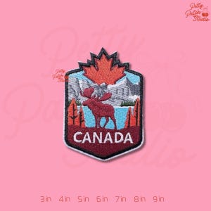 May include: Embroidered patch featuring a Canadian landscape with a moose, mountains, and a maple leaf. The patch is in a shield shape with the word "CANADA" at the bottom. Available in sizes from 3 inches to 9 inches.