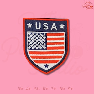 May include: Embroidered patch featuring the American flag design with the word "USA" in white letters. The patch has a shield shape with a navy blue border and red and white stripes. The patch measures 3 inches to 9 inches.