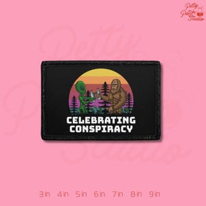 May include: Black patch with the text "CELEBRATING CONSPIRACY". The patch features a green alien and a brown Bigfoot holding bottles, set against a sunset and forest backdrop. The patch measures 3 inches by 4 inches.