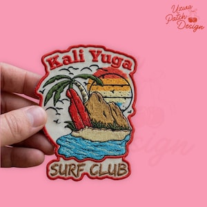 May include: Embroidered patch with a surf club theme. The patch features a red surfboard, palm tree, and a mountain scene with a sunset. Text includes "Kali Yuga" and "Surf Club" in a retro font. The patch is bordered in red.