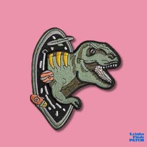 May include: Embroidered patch featuring a green Tyrannosaurus Rex emerging from a portal with planets and a spaceship. The patch has a black border and yellow accents on the dinosaur. The background is pink.