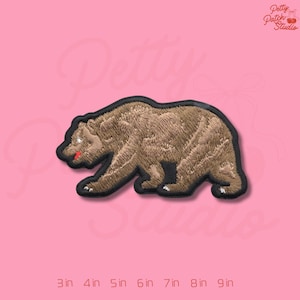 May include: Embroidered brown bear patch with black border. The bear has a red tongue and white claws. The patch is on a pink background with the text "Petty Patch Studio" and size indicators from 3 to 9 inches.