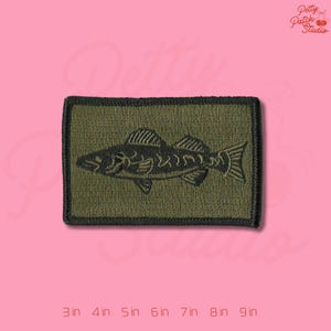 May include: A white ceramic mug with a black handle and the text "But First, Coffee" in a bold, black font. The mug is filled with a dark liquid, likely coffee, and sits on a light-colored surface.