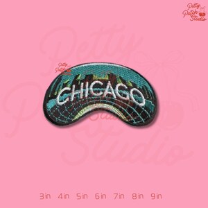 May include: Embroidered patch featuring the city skyline of Chicago, with the city name in white lettering. The patch has a curved shape and is primarily teal, brown, and black. The patch is approximately 3 inches wide.