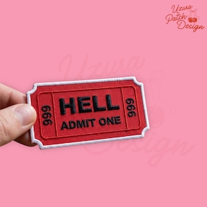 May include: A red embroidered patch in the shape of a ticket with the word "HELL" in black block letters. The text "ADMIT ONE" is below. The numbers "666" are on each side. The patch is held by a hand.