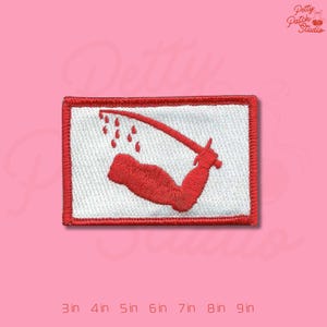 May include: Embroidered patch featuring a red arm holding a curved blade, with red droplets. The design is on a white background, framed by a red border. The patch is rectangular and measures from 3 to 9 inches.