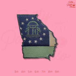 May include: Embroidered patch in the shape of the state of Georgia, featuring the state flag design. The patch has a blue background with white stars and the state seal. The bottom portion is green. The patch is approximately 3 inches to 9 inches in size.