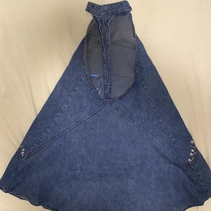 Puede incluir: Un vestido halter de mezclilla azul con falda acampanada. El vestido presenta costuras decorativas a lo largo de las costuras y un peque&ntilde;o bordado floral cerca del dobladillo. El cuello halter est&aacute; abierto por la espalda.