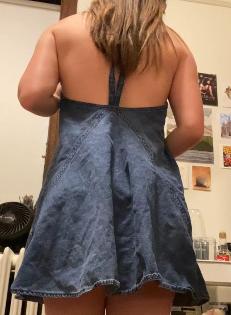 Puede incluir: Vestido halter de mezclilla en un lavado azul medio. El vestido presenta una falda acampanada y un cuello halter con cierre de lazo. Las costuras est&aacute;n acentuadas con pespuntes. Es un estilo casual de verano.