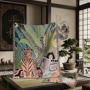Peut inclure: Une couverture décorative avec un motif de tigre et de feuillage tropical. Une personne lit un journal avec le texte "Le Monde". La couverture est posée sur un tatami dans une pièce de style japonais.