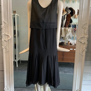 May include: A black sleeveless midi dress with a sheer overlay and a slightly flared skirt.