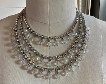 May include: A multi-layered crystal necklace with a silver chain and teardrop-shaped crystal accents.