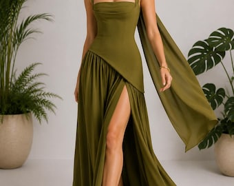 May include: An olive green floor-length dress featuring a square neckline, a structured bodice, and a draped scarf detail attached at the neck. The skirt includes a high side slit and a gathered waistline, creating a flowing silhouette.