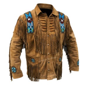 May include: A tan suede jacket featuring long fringe detailing on the chest, sleeves, and pockets. The garment includes blue beaded panels with eagle motifs on the shoulders, horizontal leather accents, and circular blue beaded patches on the sleeves.